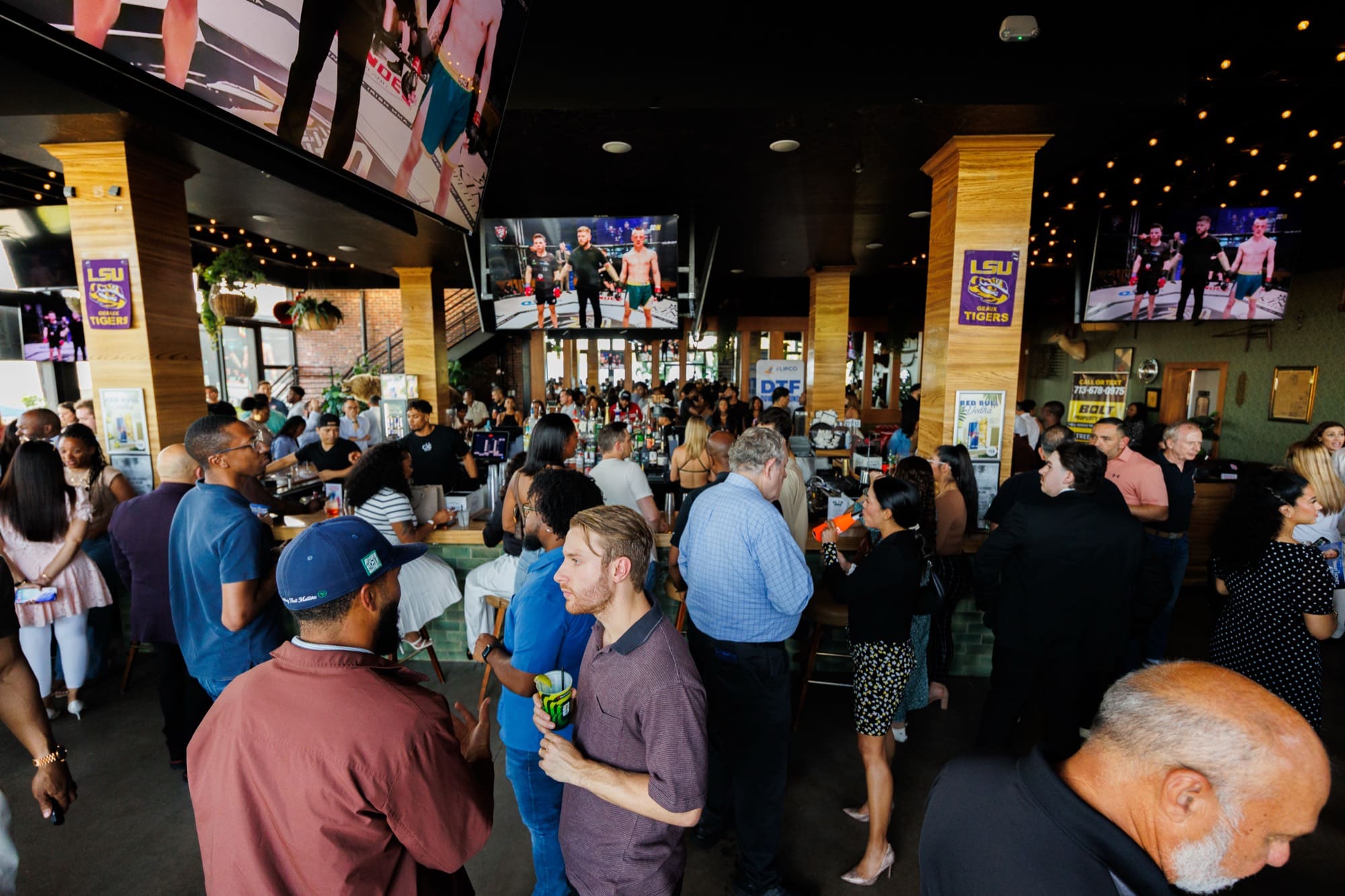 A full room of guests gathered around the bar at a Madu Rooms social in Houston.